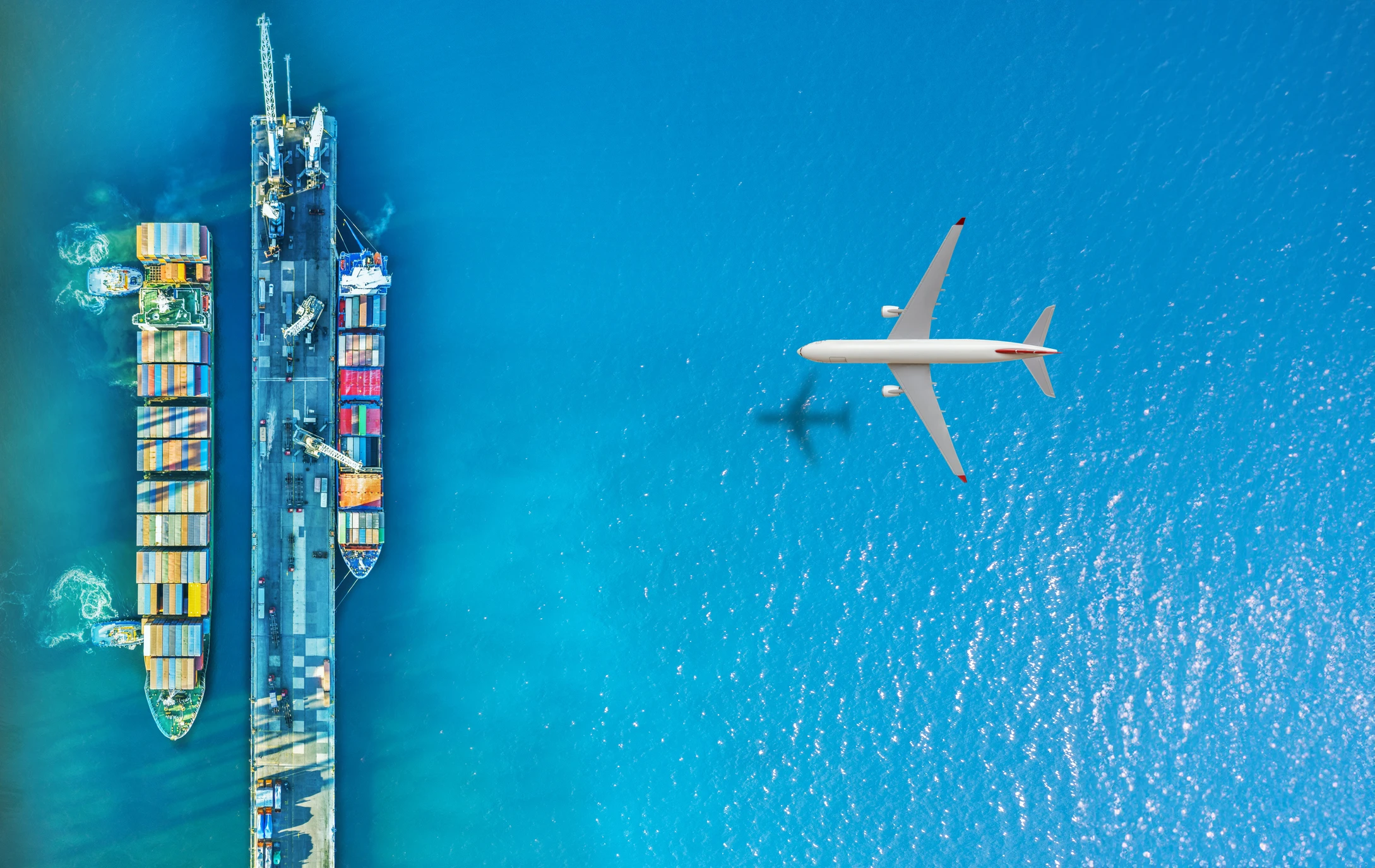 Cargo Airplane flying above container ship. Certified international chemical logistics in action, with specialty chemical containers prepared for global shipment by Qemi International.